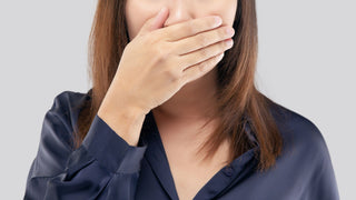 Frau mit Mundgeruch hält sich den Mund zu